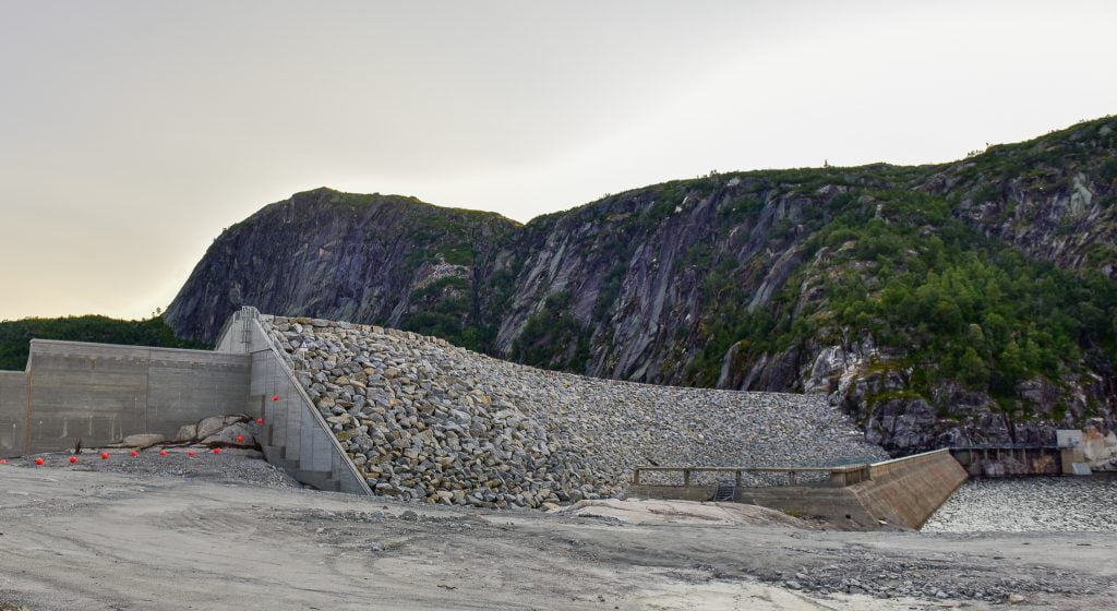 Den nye steinfyllingsdammen ved Langevatn som ruvar høgt over den ganle betongdammen. Foto.